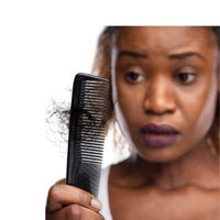 Femme constatant la casse de ses cheveux dans un peigne lors d'une routine capillaire pour cheveux crépus, frisés ou bouclés.