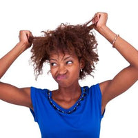 Femme confrontée à la casse des cheveux crépus avant l'utilisation des soins naturels Kaylabé.
